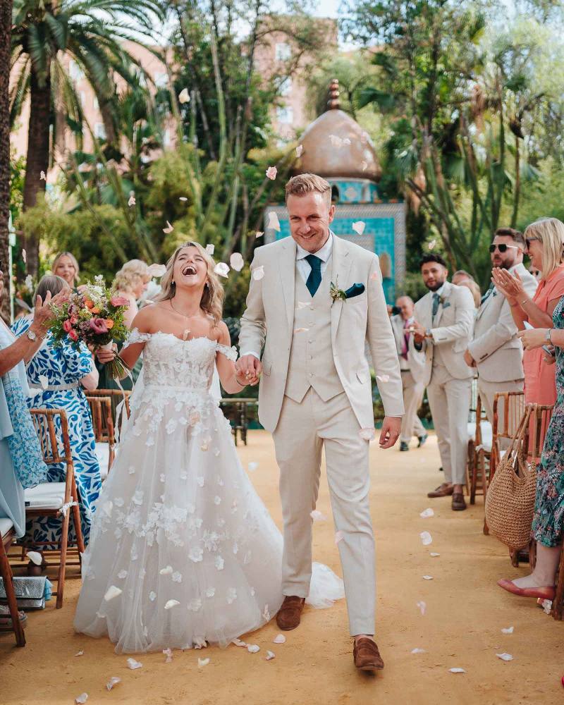 bride and groom walking down the aisle with guests cheering in hacienda villa luisa seville