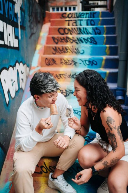La pareja se ríe comiendo polos en una escalera pintada con grafitis de la Comuna 13, en Medellín