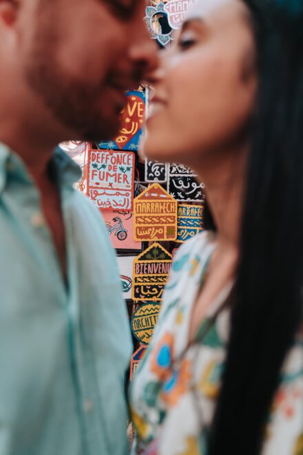 Los novios, desenfocados, casi se besan ante letreros pintados a mano con la palabra «Marrakech»