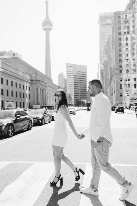 Los novios cruzan un paso de cebra de la mano con la torre CN detrás, en blanco y negro