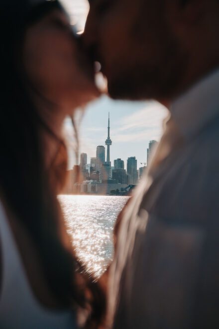 Entre las caras desenfocadas de los novios asoman la torre CN de Toronto y el lago brillando al sol