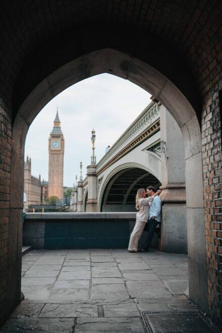 Los novios abrazados junto al puente de Westminster, enmarcados por un arco de ladrillo, con el Big Ben al fondo