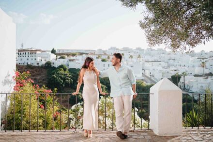 Los novios apoyados en la barandilla de un mirador, con un pueblo blanco en la ladera detrás