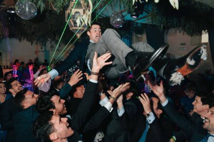 Los invitados lanzan al novio por los aires bajo bolas de espejos y rayos láser verdes