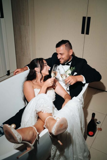 Los novios brindan con champán metidos en una bañera blanca, con la botella y el corcho en el suelo