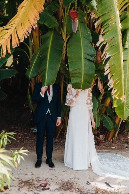 Los novios se tapan la cara con dos hojas de platanera, con la cola del vestido en el suelo
