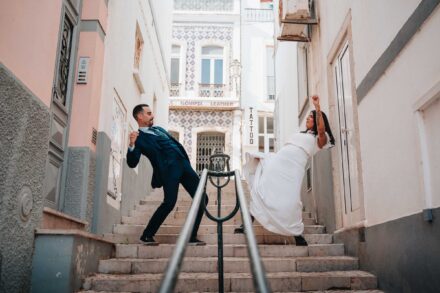 Los novios fingen una pelea en una escalera estrecha, ella lanzando una patada y él echándose atrás