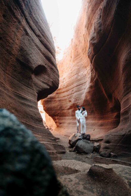 Los novios, abrazados sobre unas rocas, en el fondo de un estrecho barranco de roca rojiza erosionada
