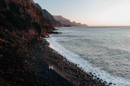 Los novios, diminutos, en una playa de cantos rodados al pie de grandes acantilados, vistos desde el aire