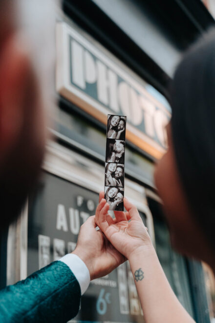 Las manos de los novios sostienen una tira de fotomatón en blanco y negro ante el rótulo «Photo»
