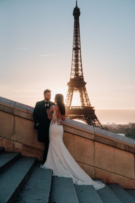 Los novios abrazados en su postboda en una escalinata de París, con la torre Eiffel a contraluz detrás