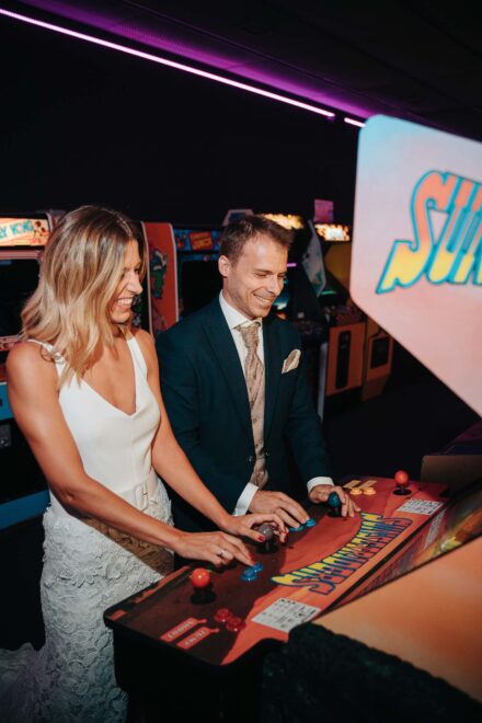 Los novios se ríen mientras juegan a la vez en una máquina recreativa de un salón de juegos