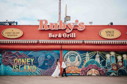 Los novios pasean de la mano ante los murales de colores del paseo marítimo de Coney Island (Nueva York)