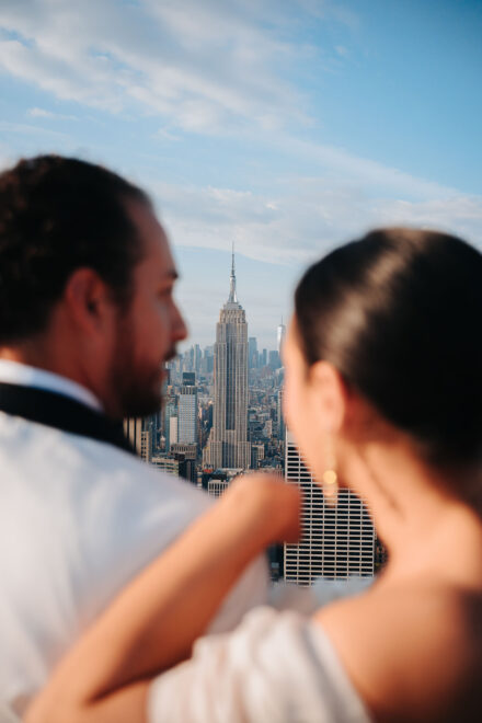 Los novios, desenfocados, se miran abrazados con el Empire State nítido entre los dos