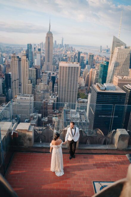 Los novios, vistos desde arriba, se dan la mano en un mirador sobre los rascacielos y el Empire State