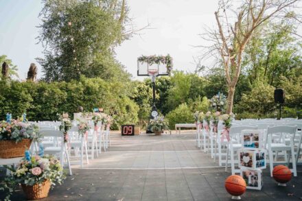 Ceremonia preparada en una pista de baloncesto, con la canasta adornada de flores y balones junto a las sillas
