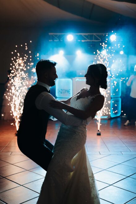Los novios bailan a contraluz entre dos fuentes de chispas frías y humo azul