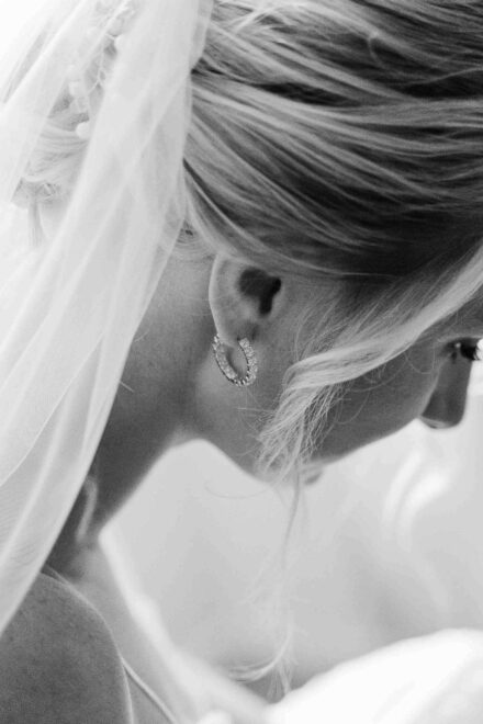 La novia, de espaldas y con el pelo recogido, deja ver un aro de brillantes bajo el velo, en blanco y negro