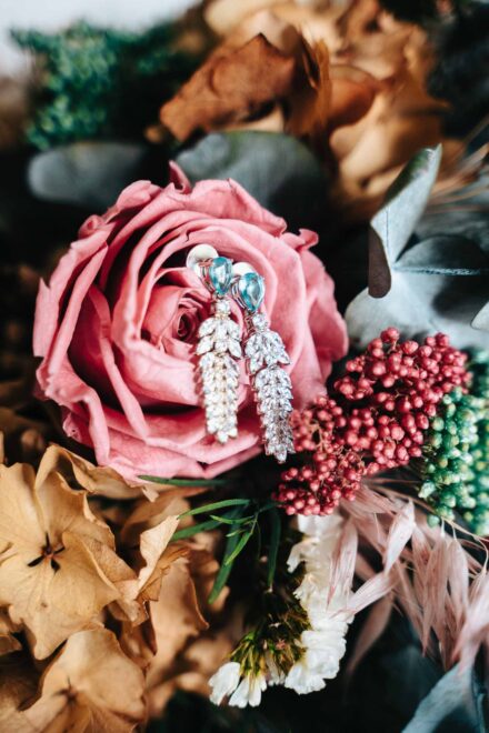 Los pendientes de la novia, con piedra azul y cristales, colgados de una rosa del ramo