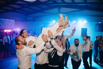 Los invitados levantan en volandas a la novia, que ríe con los pies en alto, en la pista de baile